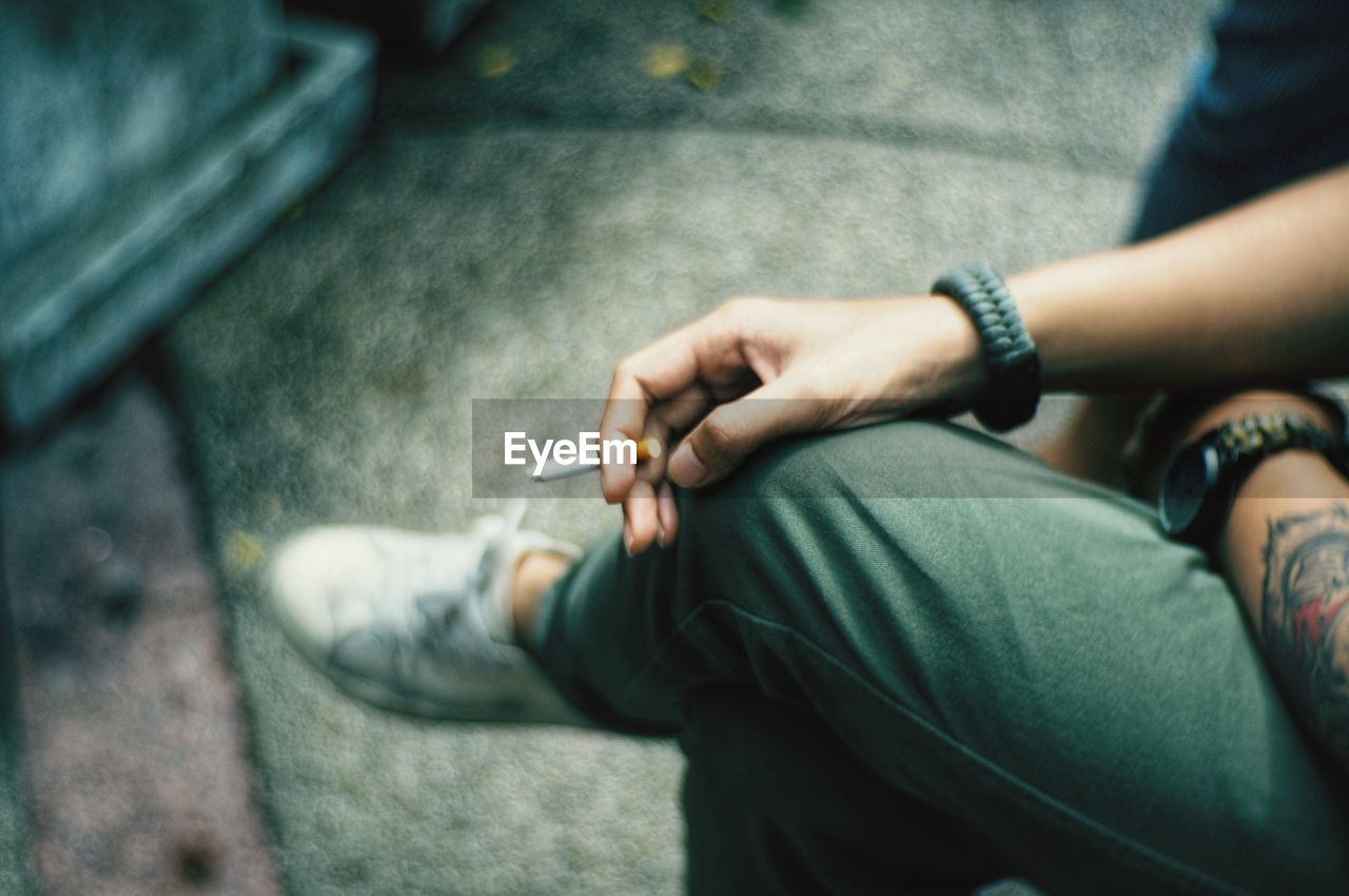 Low section of man holding cigarette