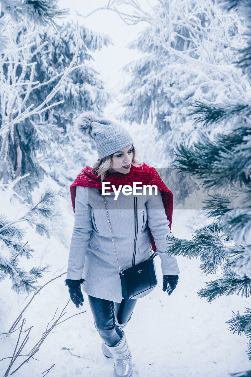 High angle view of woman wearing warm clothing while walking amidst trees on snowy field