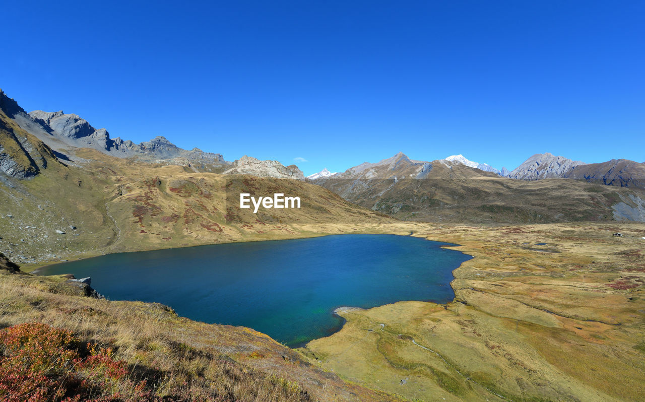 SCENIC VIEW OF LAKE AND MOUNTAINS AGAINST BLUE SKY