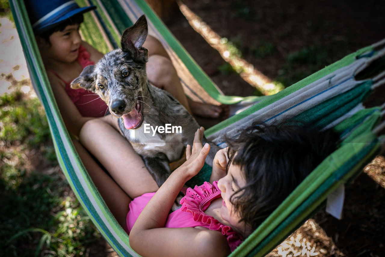 Two girls in hammock playing with the dog