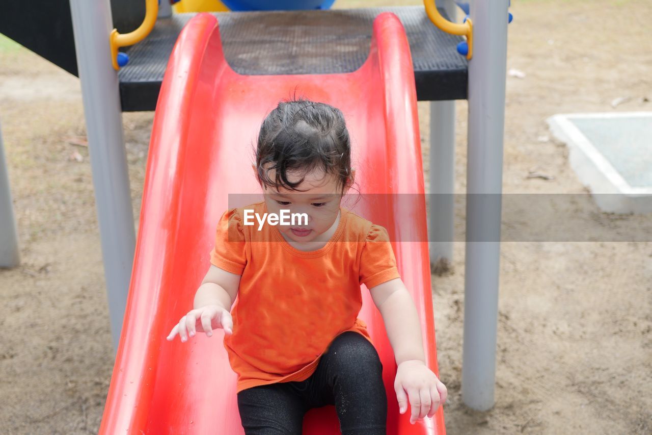 High angle view of girl sliding on slide at playground