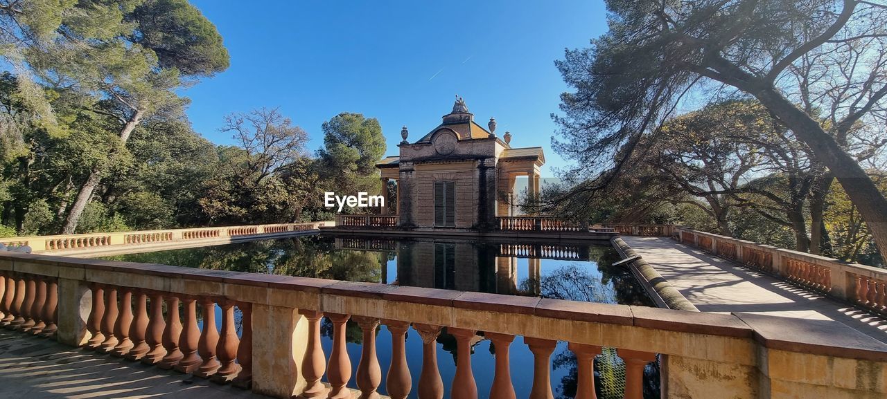 architecture, tree, built structure, plant, estate, nature, building exterior, sky, travel destinations, bridge, railing, no people, building, place of worship, day, religion, water, blue, travel, the past, history, outdoors, clear sky, belief, tourism, city, spirituality