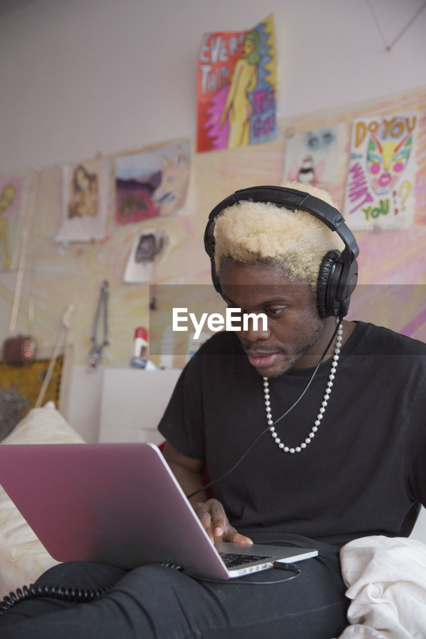 A young man wearing headphones with a laptop