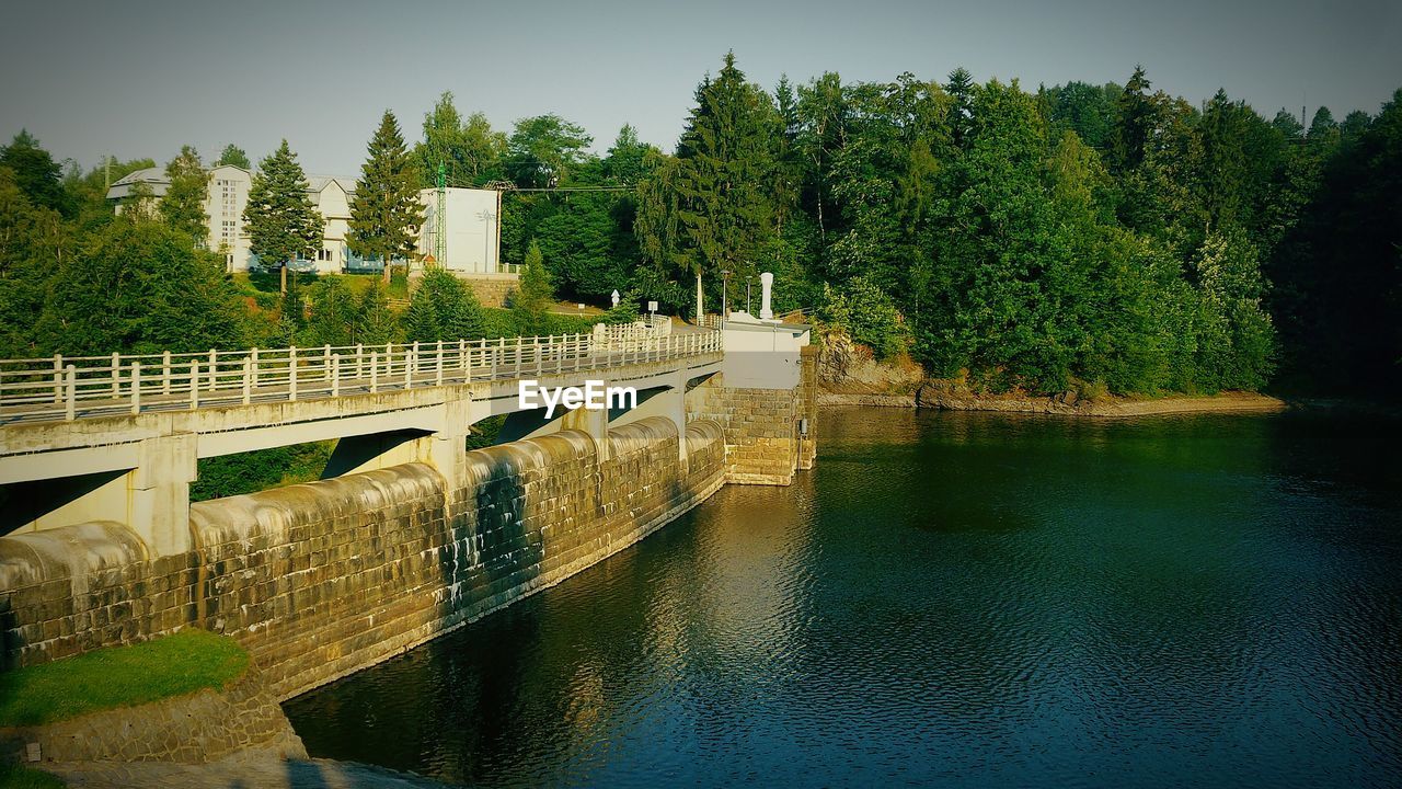 Bridge over calm canal against trees