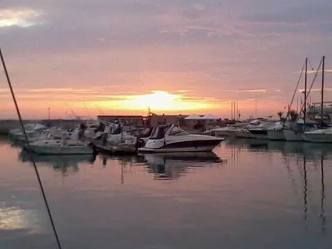 SAILBOATS IN SEA AT SUNSET