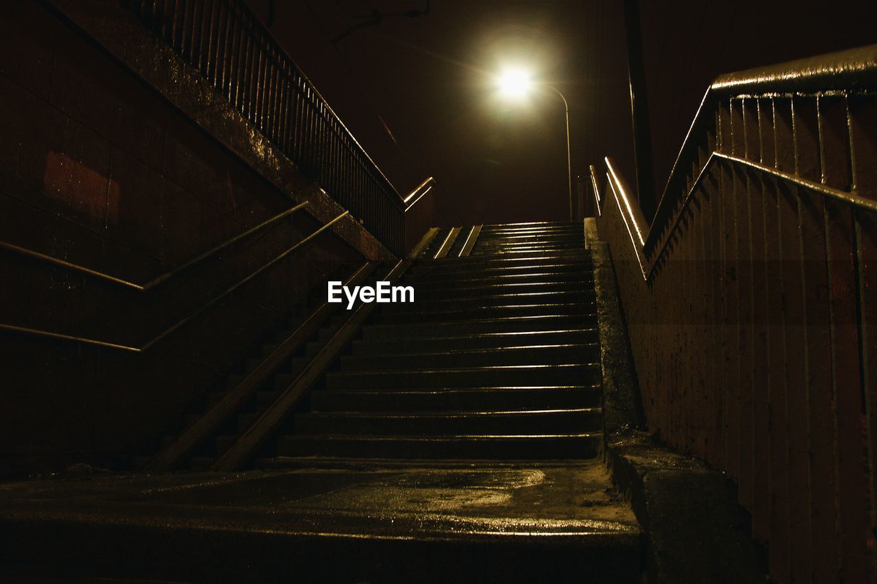 Low angle view of steps leading towards illuminated street light during night