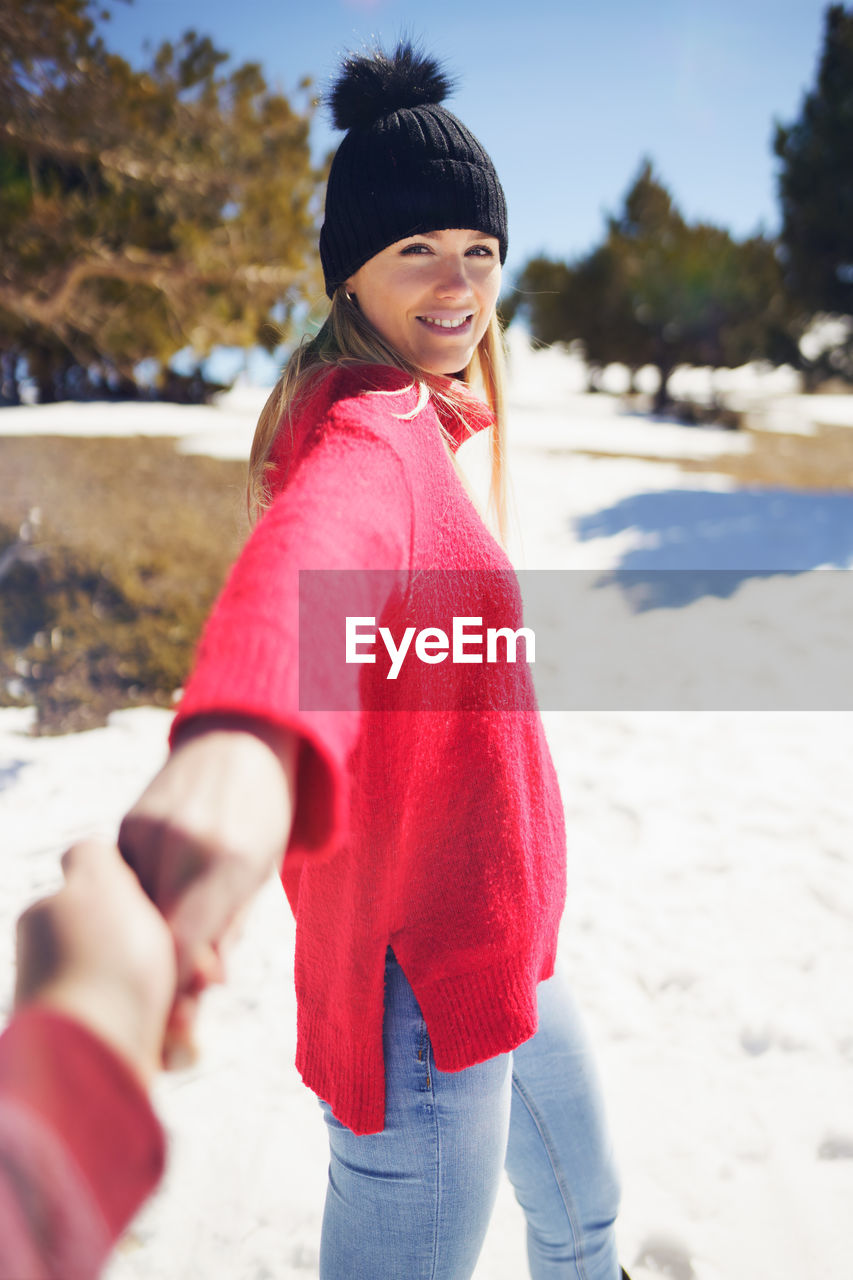 Smiling woman standing on snow covered land