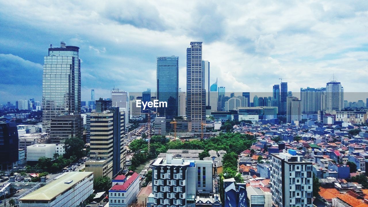 HIGH ANGLE VIEW OF CITYSCAPE AGAINST CLOUDY SKY