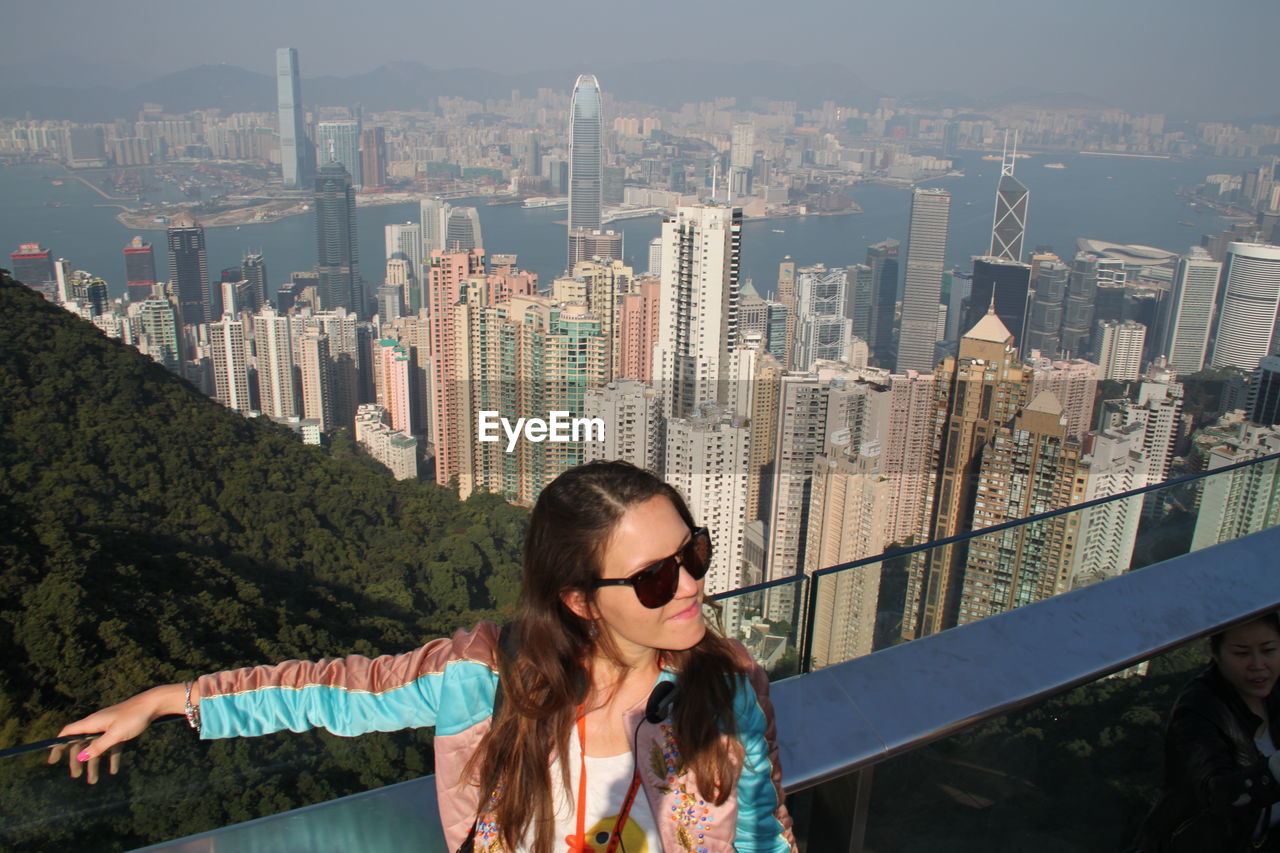 Young woman standing against victoria harbour in city