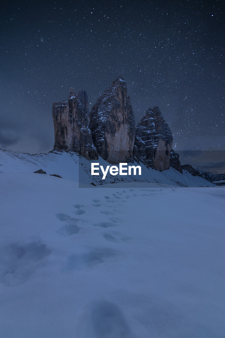 SNOW ON FIELD AGAINST SKY AT NIGHT