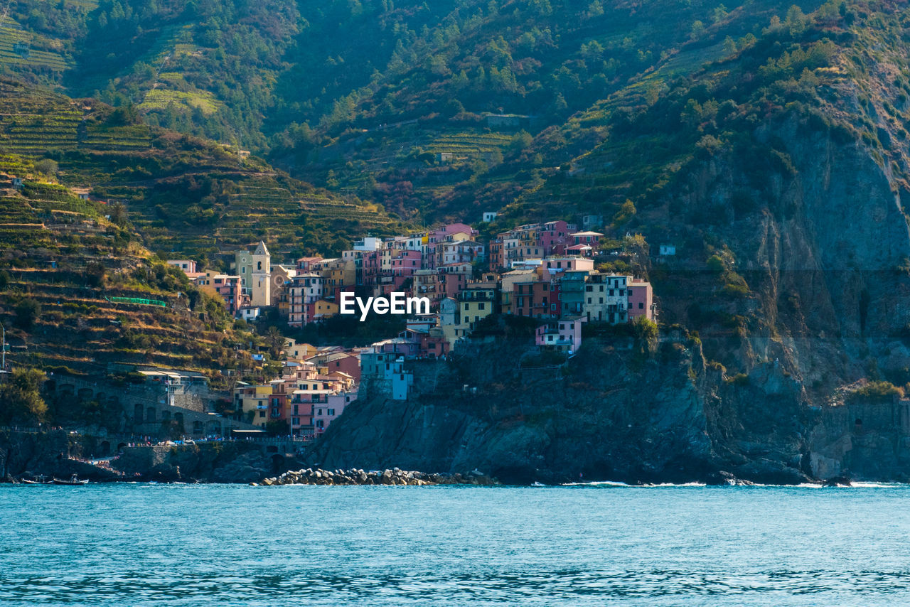 Scenic view of sea by mountain against sky