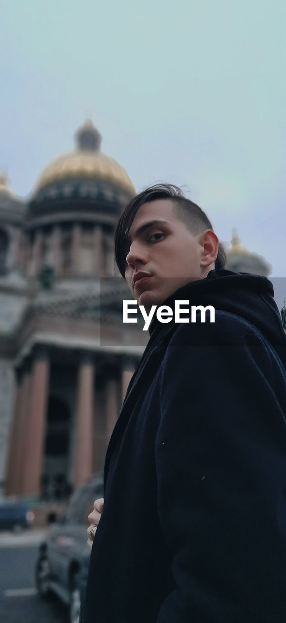 Portrait of young man standing against saint isaac's cathedral in saint petersburg, russia. 