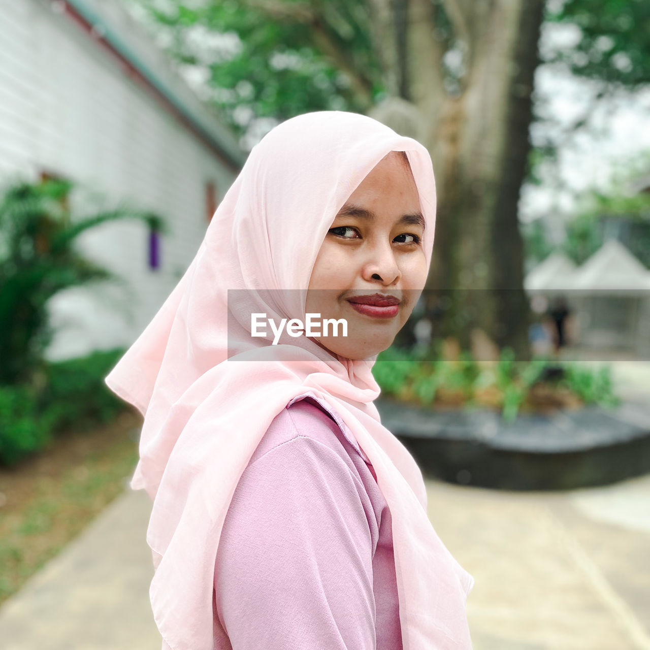 Portrait of hijab muslim young woman standing against trees
