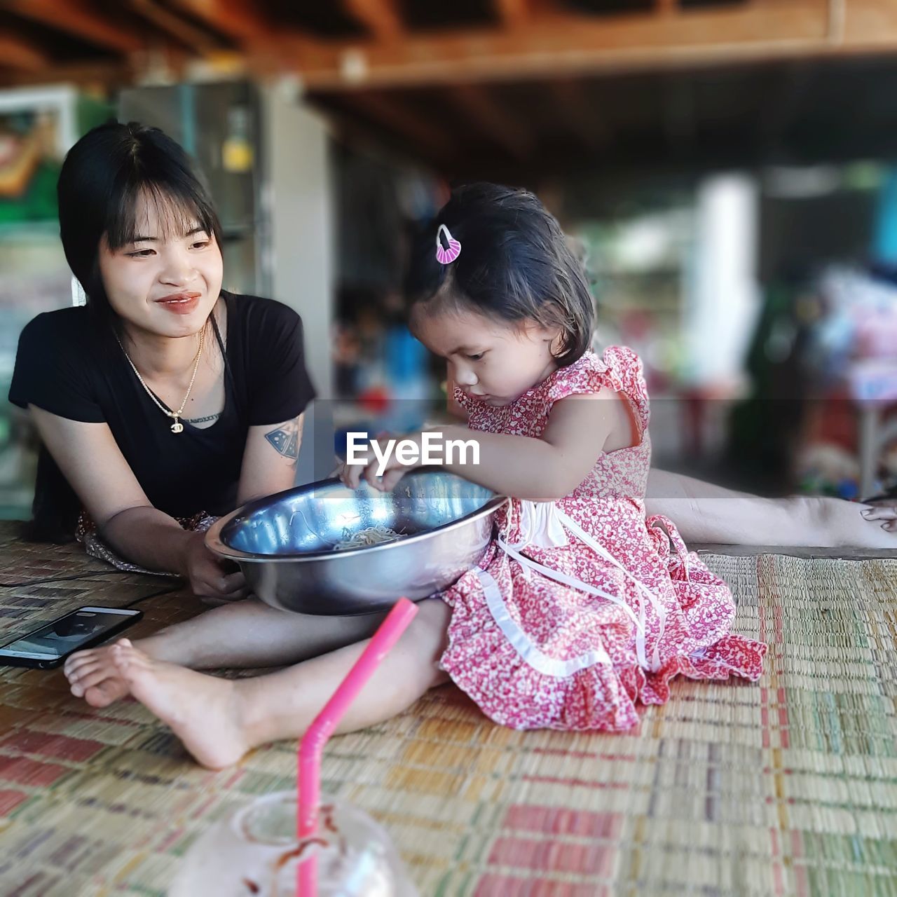 Mother looking at daughter sitting with bowl