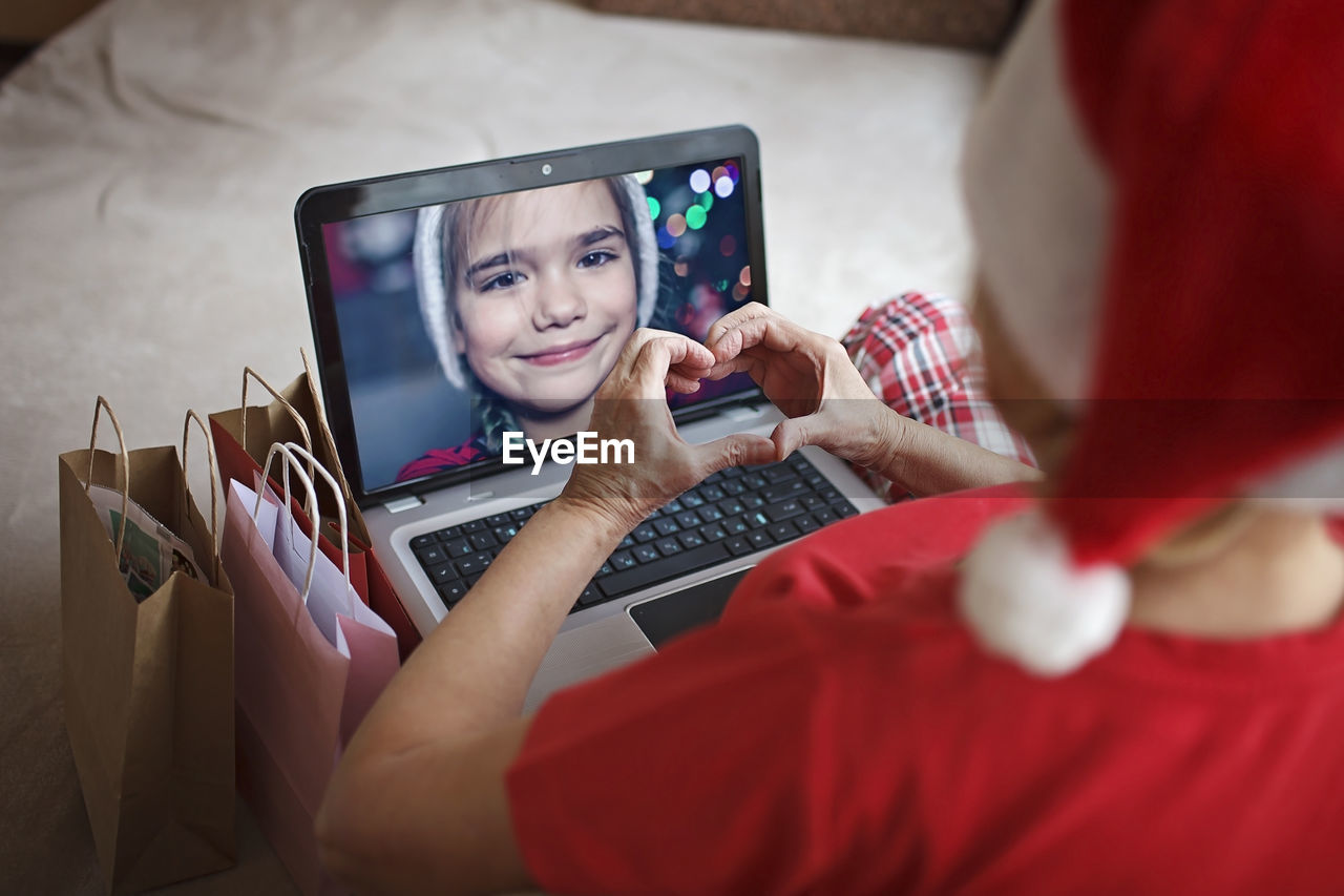 Safe online christmas celebration. senior woman in santa red hat celebrating with family virtually