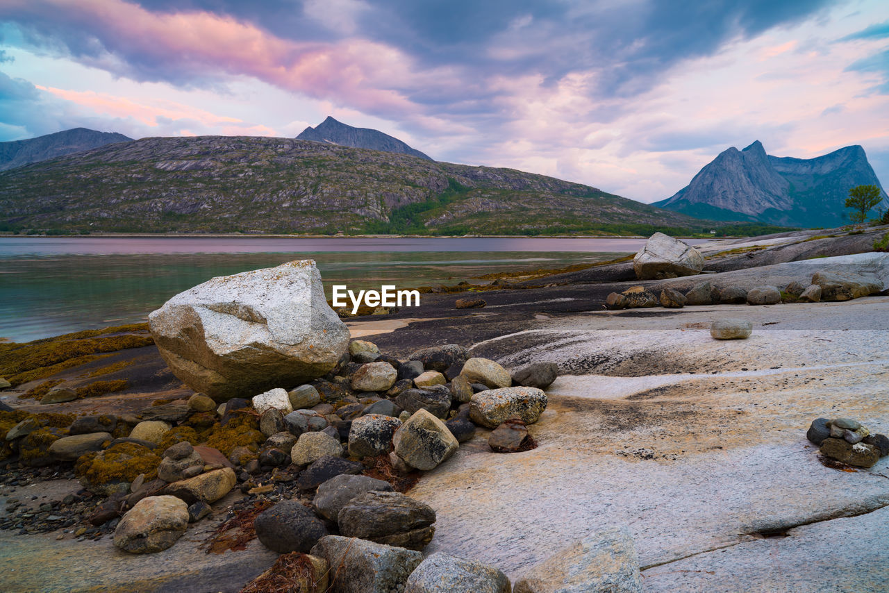 Rocks by lake against sky