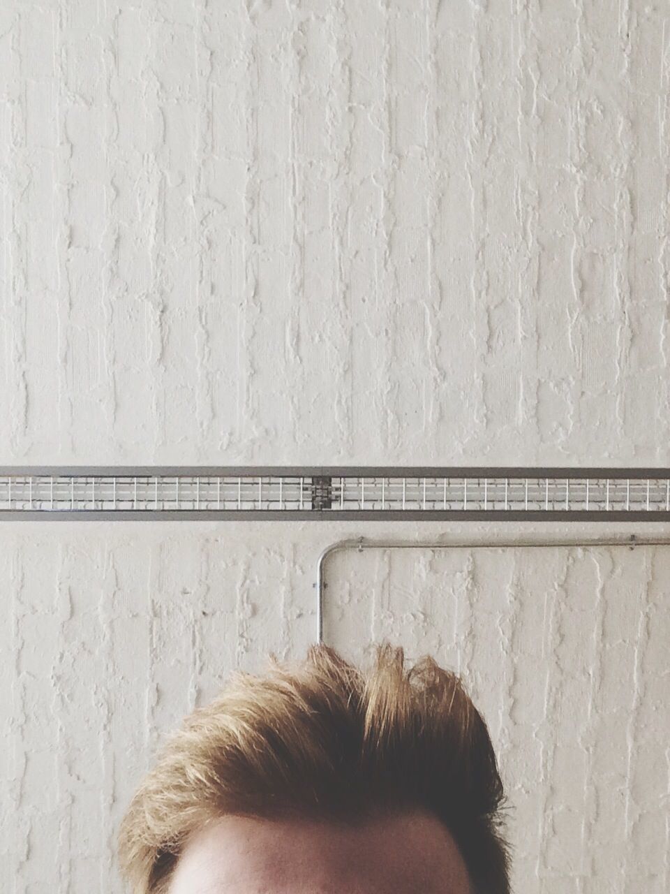 Cropped image of man with spiky hair against wall