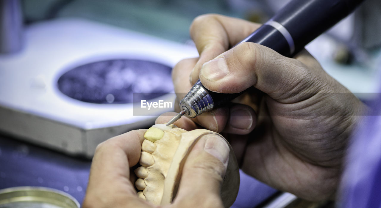 Cropped hands of person cleaning dentures in clinic