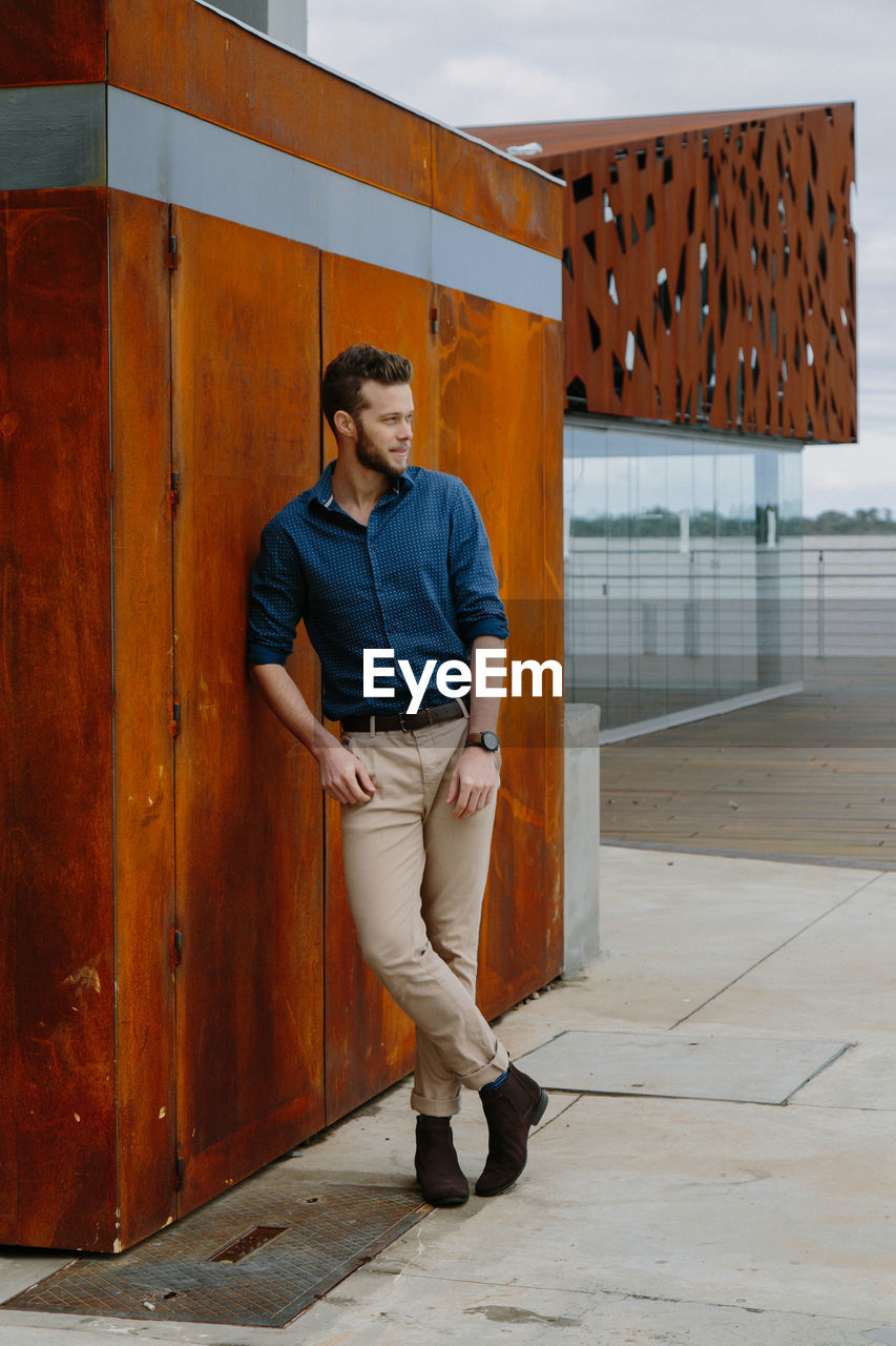 Full length of young man standing against building