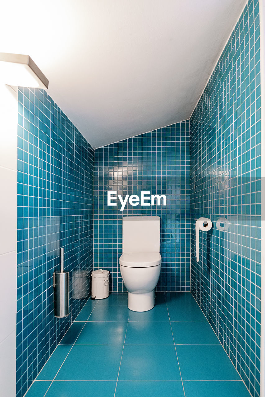 Front view of blue tiles walls in spacious modern bathroom in daylight