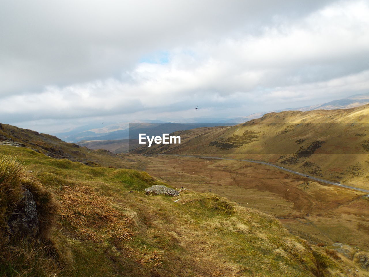 Scenic view of green landscape against cloudy sky