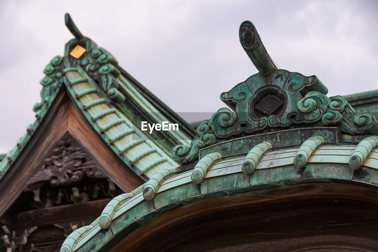 Low angle view of roof tiles and decoration on japanese temple against sky