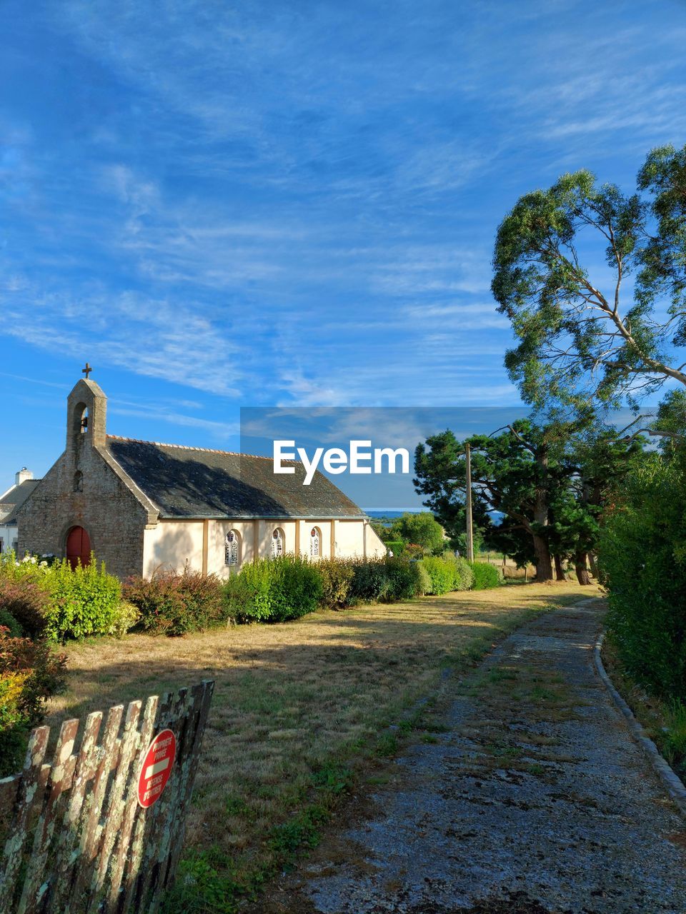 Road amidst trees and church against sky