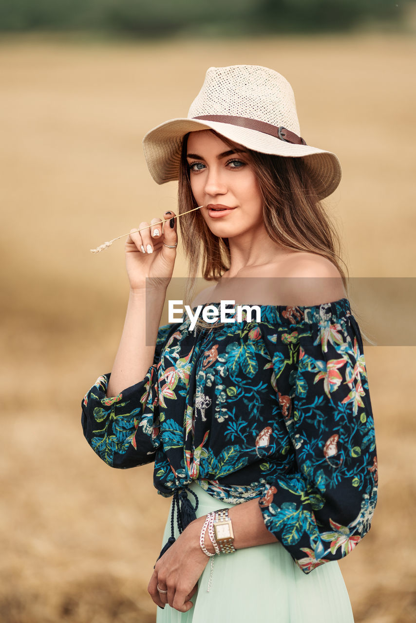 Portrait of beautiful young woman wearing hat standing outdoors