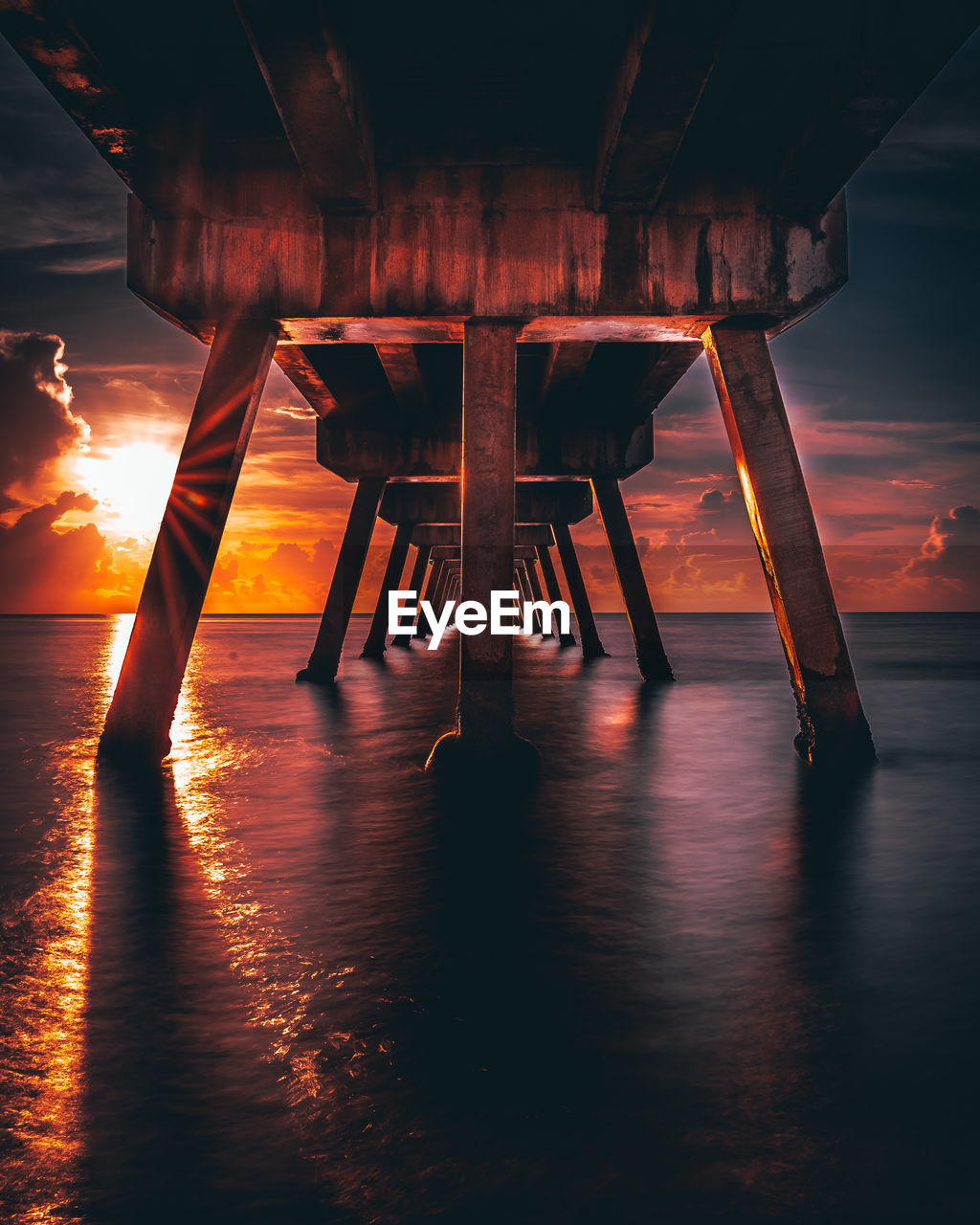 Pier on sea against sky during sunset