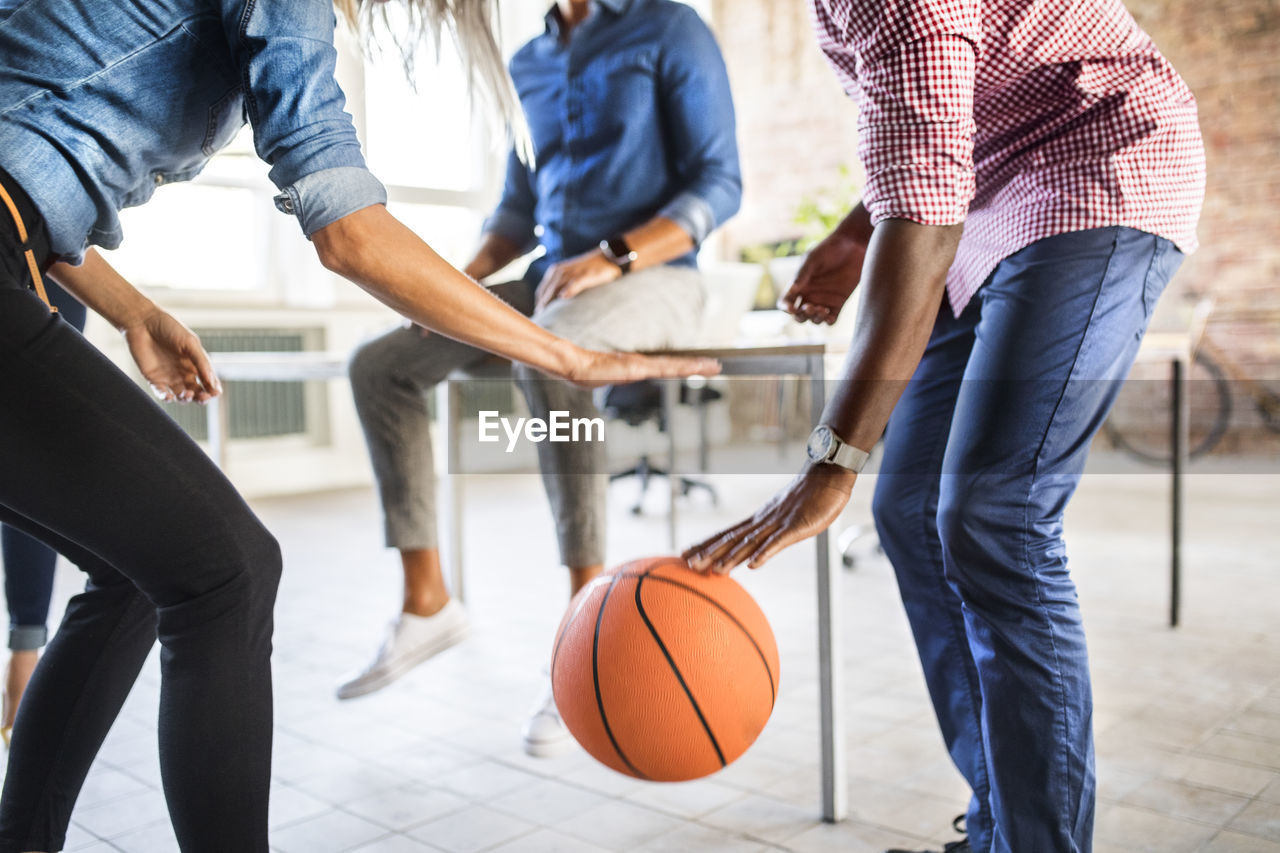 Colleagues playing basketball in office