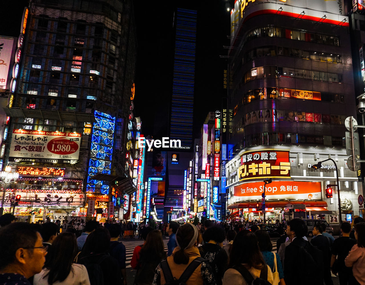 People against illuminated modern buildings in city at night