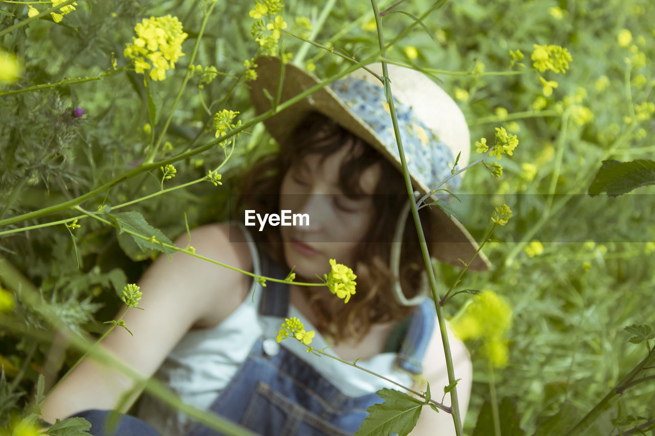 Young woman wearing hat while sitting amidst plants