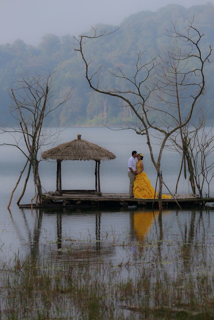 Couple standing on pier amongst lake
