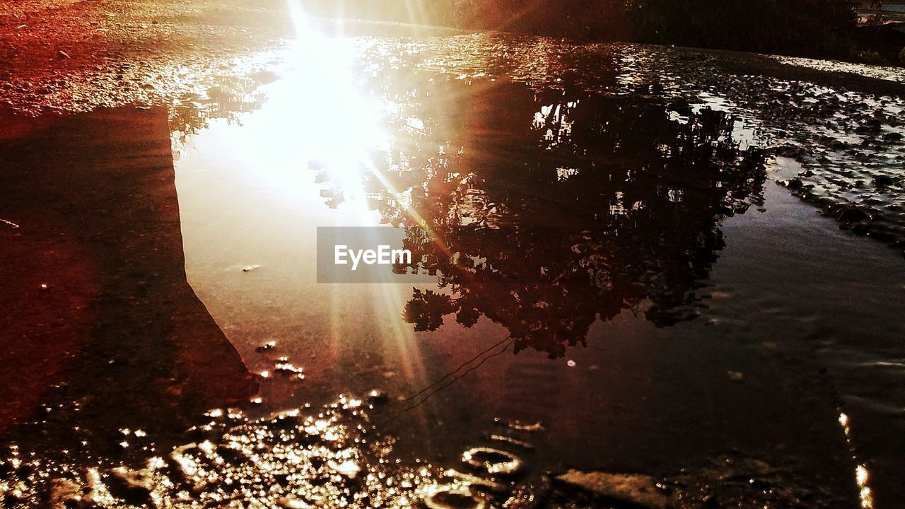 CLOSE-UP OF ILLUMINATED REFLECTION IN PUDDLE