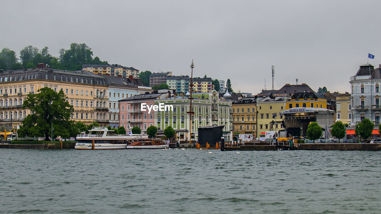 BUILDINGS BY RIVER AGAINST SKY