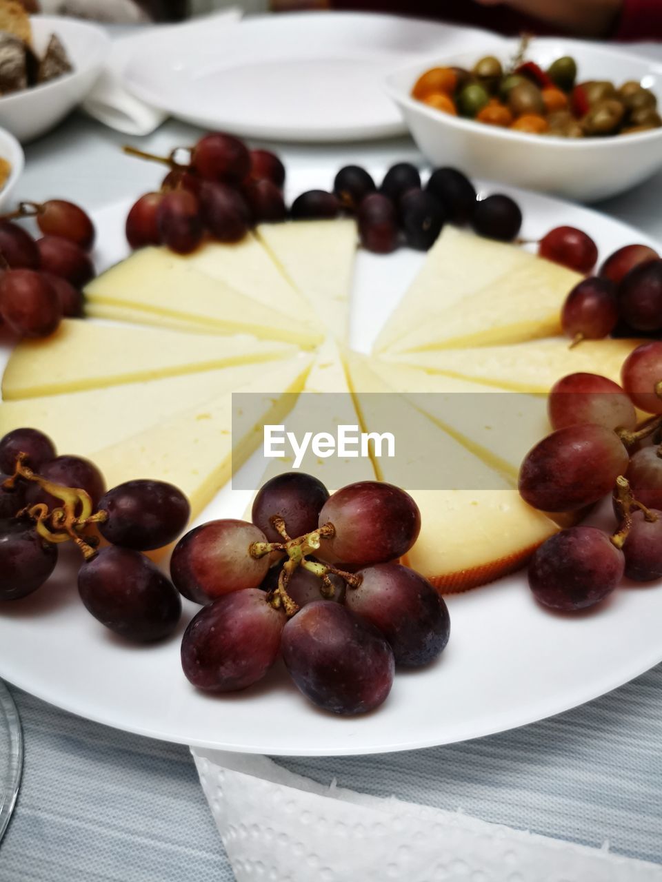 food and drink, food, fruit, healthy eating, grape, freshness, wellbeing, produce, no people, olive, plate, indoors, table, abundance, fig, dairy, meal, still life, sweet food, studio shot, wood, red grape, variation, cheese, large group of objects, chestnut