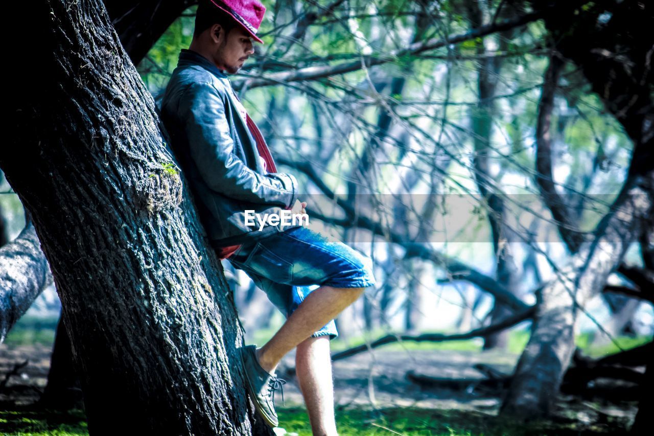 MAN SITTING ON TREE TRUNK