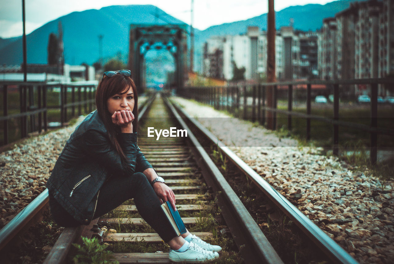 Girl sitting on railroad track