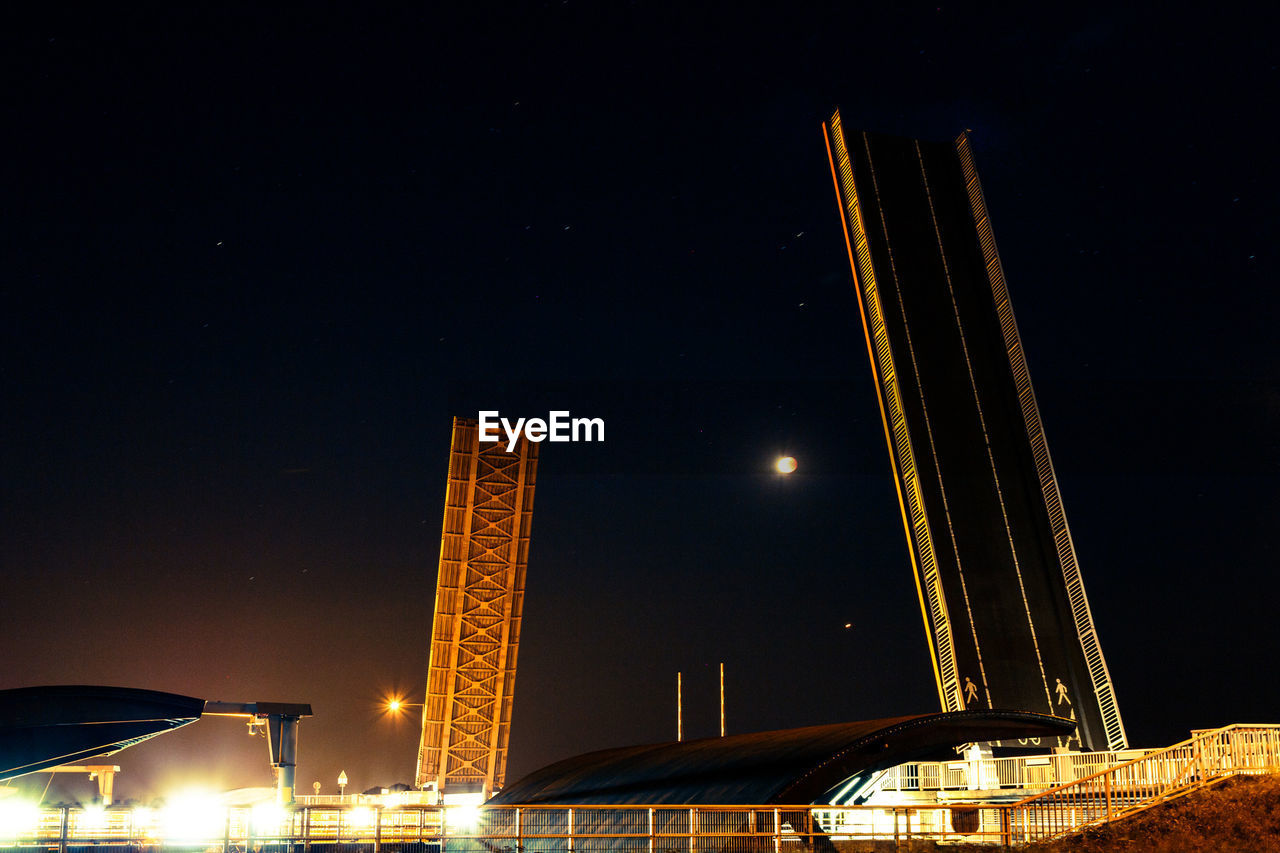 Low angle view of illuminated bridge against sky at night