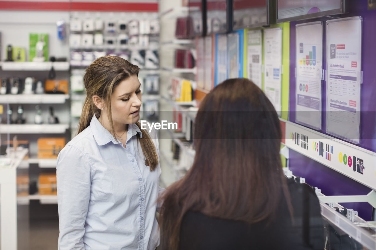 Saleswoman assisting woman in electronics store