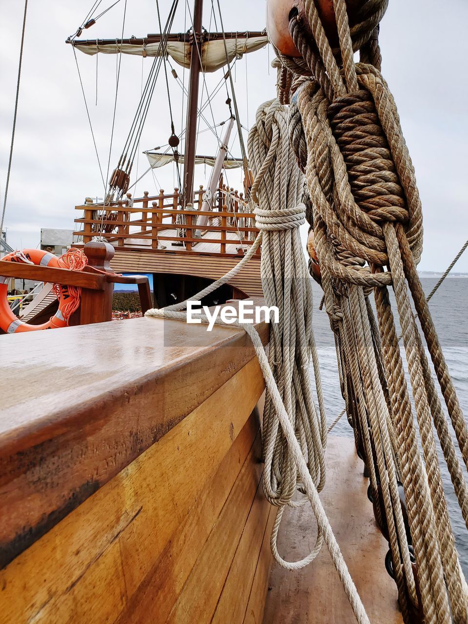 SAILBOAT TIED TO WOODEN POST IN SEA