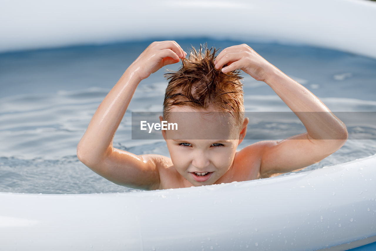 Portrait funny white toddler with ripped hair in the pool.