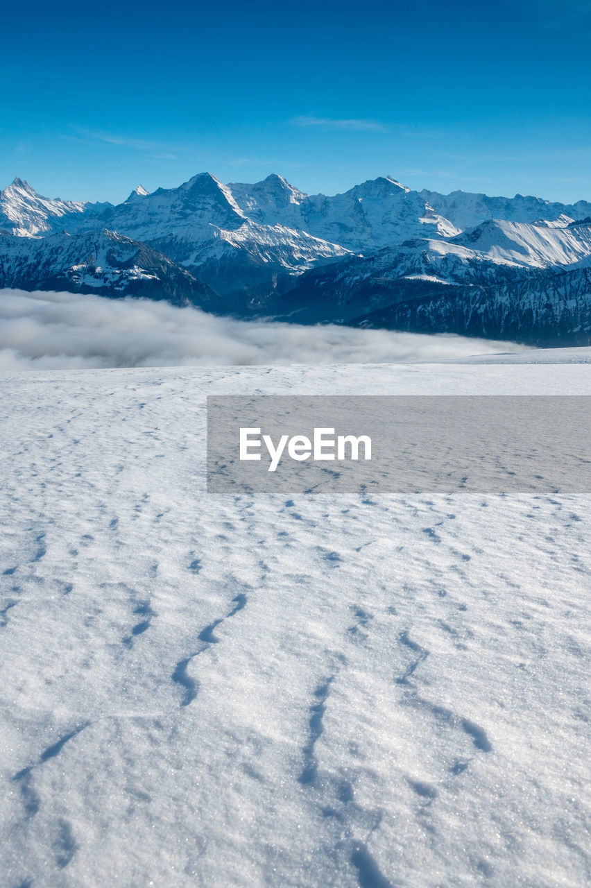 Scenic view of snowcapped mountains against blue sky