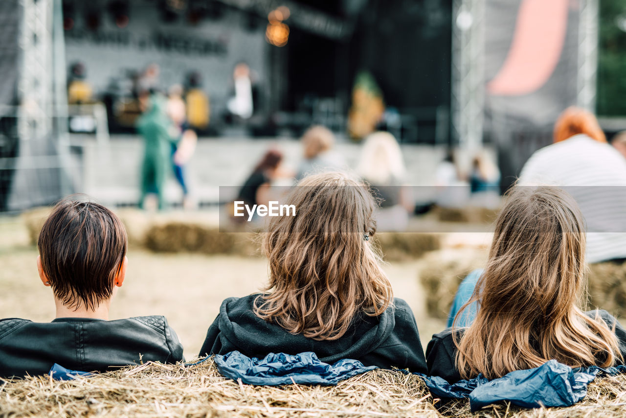 REAR VIEW OF PEOPLE SITTING ON STAGE