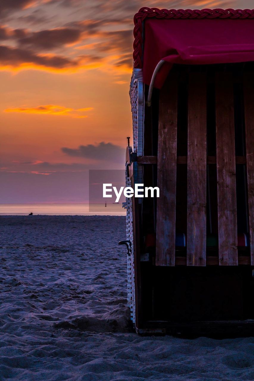 Hooded chair at beach during sunset