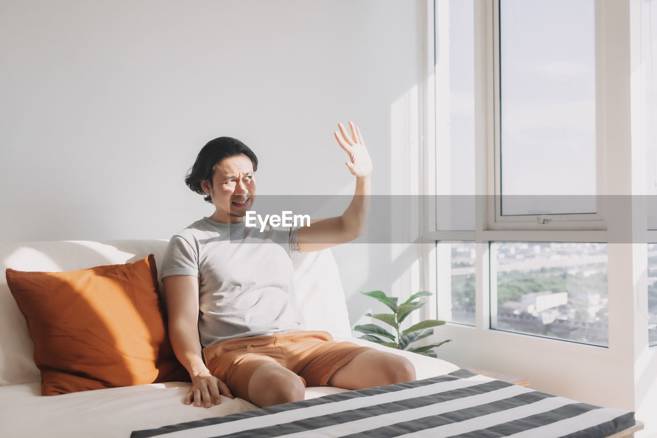 Man shielding eyes while sitting on bed
