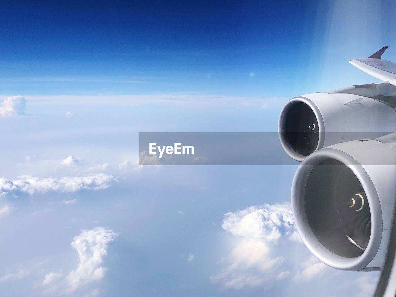 Cropped image of airplane flying over clouds seen through window