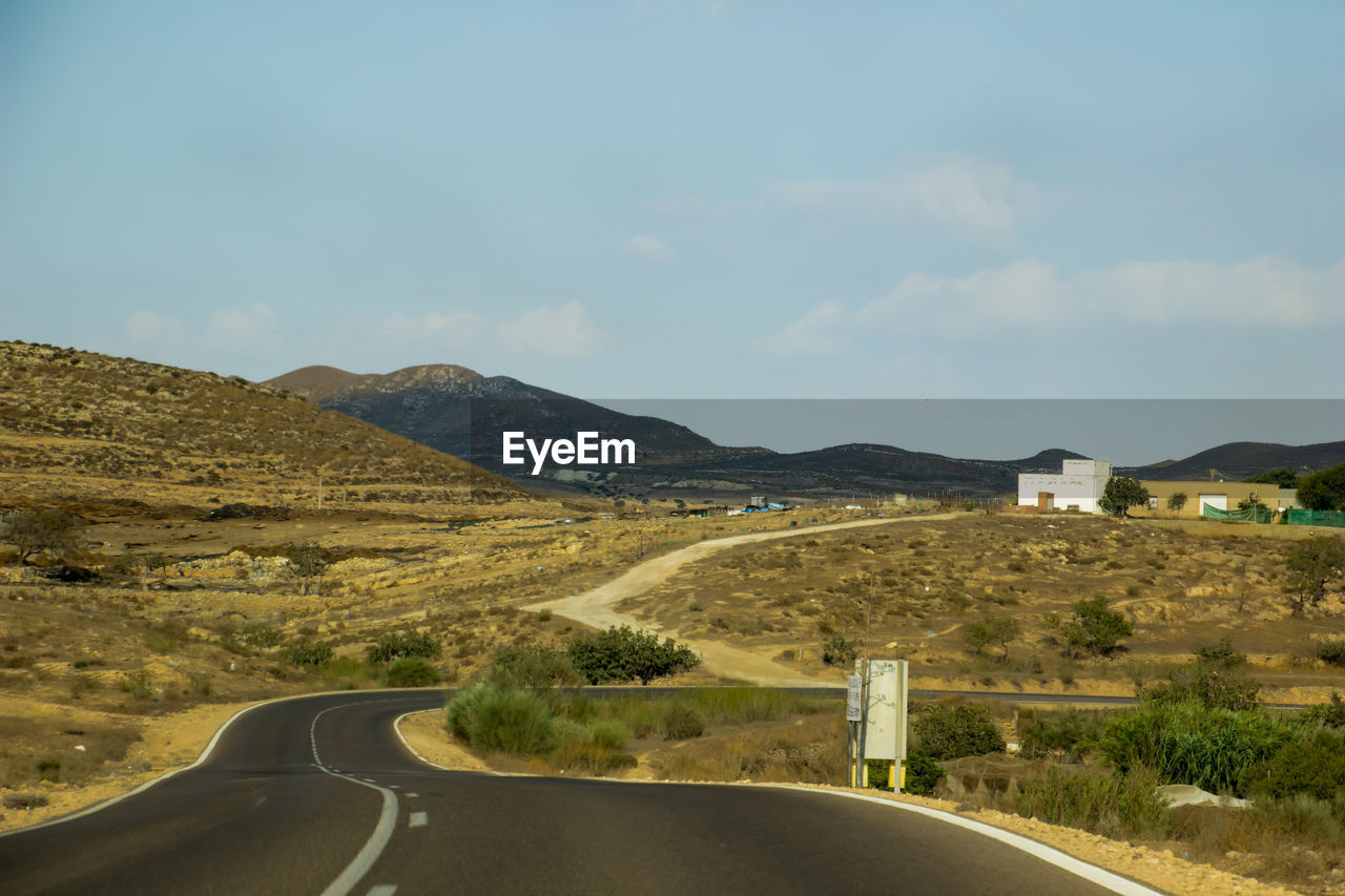 Road leading towards mountains against sky