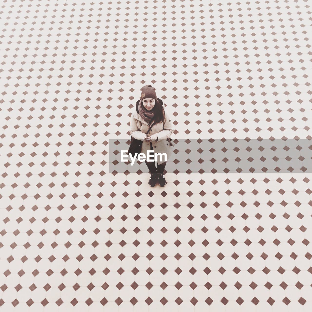 High angle portrait of woman standing on tiled floor