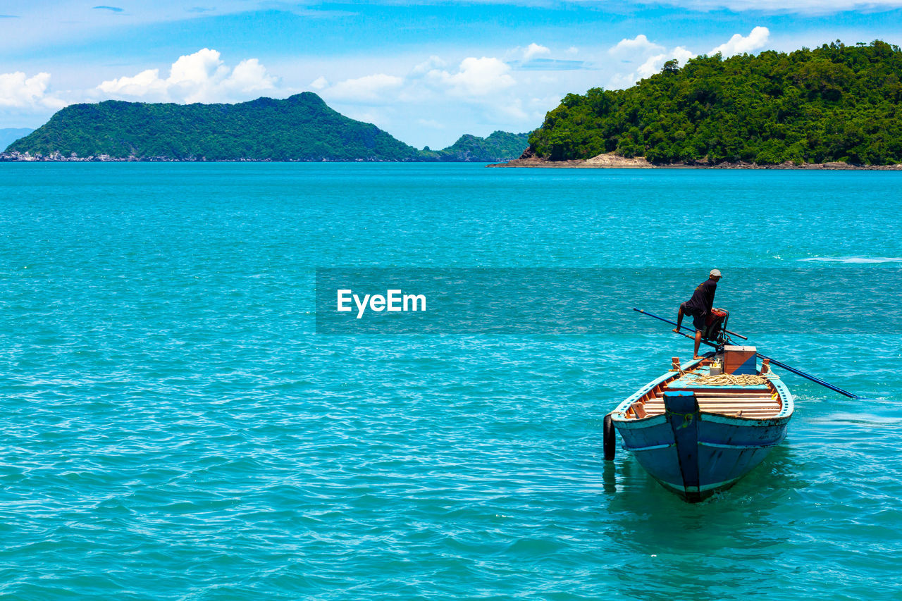 MAN ON BOAT AGAINST SEA